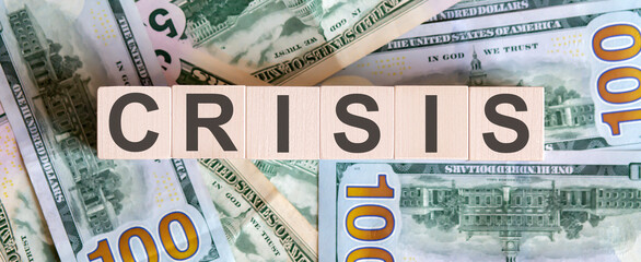 Concept words CRISIS on wooden blocks on a beautiful background from dollar bills.