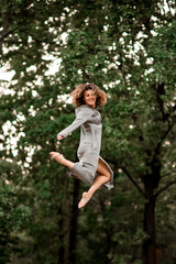 Naklejka na ściany i meble happy woman with bend knees jumps high in the air