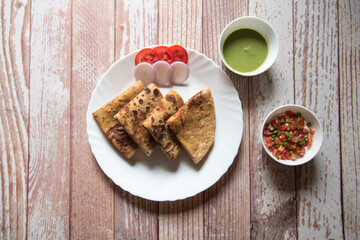 Top view of Indian popular breakfast dish alu paratha in a plate. Alu paratha is mashed potato stuffing in wheat bread.