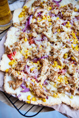 Very tasty and appetizing pizza with ham, red onion, corn, cheese. Thin Italian pastry. Close-up, top view.