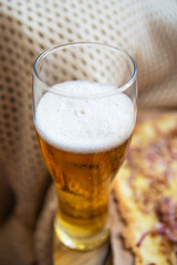 A glass of cold light beer. Very tasty and delicious pizza with tuna, red onion, cheese. Thin Italian pastry. Close-up, top view.