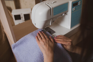 A woman seamstress sews on a sewing machine at home.