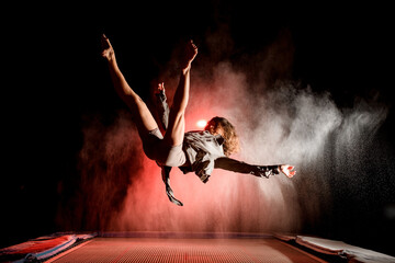 active woman bouncing on trampoline and performs trick in the air at dark time