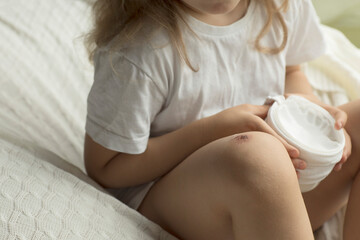 Girl of 5 years old is applying the cream on her skin