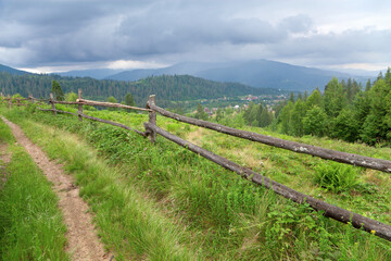Fototapeta na wymiar Mountain road with a wooden fence, foggy mountains in the distance.