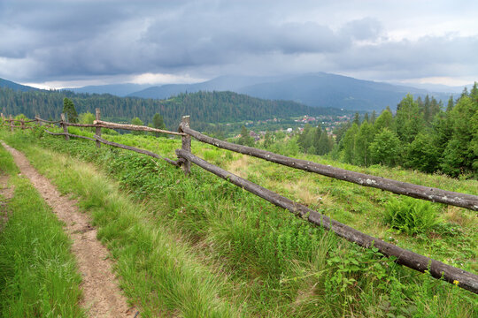 Mountain road with a wooden fence, foggy mountains in the distance.
