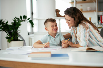 Fototapeta premium Mother helping her son with homework at home. Little boy learning at home..