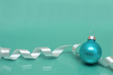 Christmas decorations on green background.One ball and ribbon