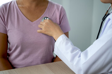 Doctor evaluates the patient with a stethoscope and records the results, health medical checkup concept