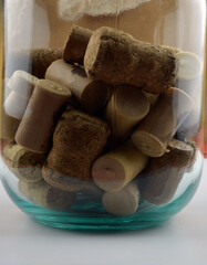 
a lot of wine corks lie in a transparent jar on a white background