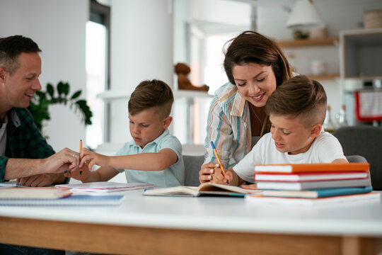 Parents helping the kids with their homework. Litlle boys learning at home.