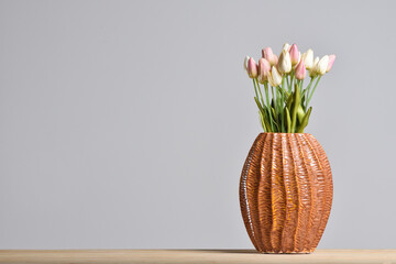 Modern embossed ceramic vase with tulips on a gray background with a copy space