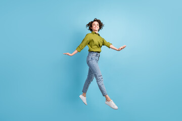 Fototapeta na wymiar Photo portrait of graceful woman jumping up hands to sides isolated on pastel light blue colored background