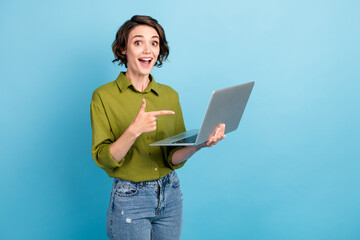 Photo portrait of woman pointing at laptop holding in hand isolated on pastel light blue colored background
