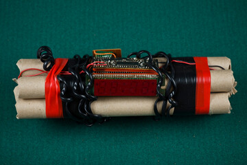 Studio photo of home made bomb/dynamite with digital timer  wrapped with black wires and red duct tape. Isolated on green background.