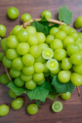 Shine Muscat Grape with leaves in wooden background, Green grape in Bamboo basket on wooden table in garden.