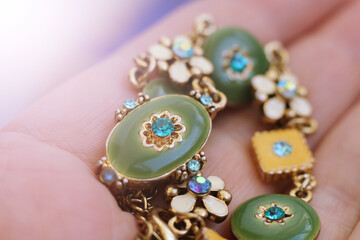 A hand holding a bracelet of green beads