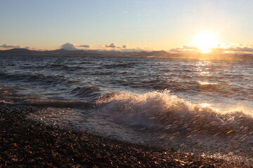 waves hit the shore at sunset