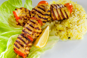 Plate of grilled chicken kebab served with rice.