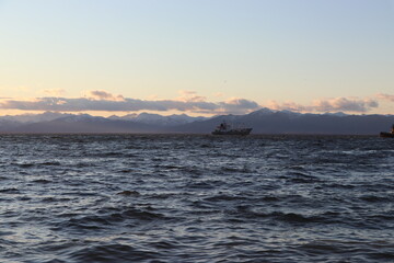 Fototapeta premium a warship sails in the distance at sunset