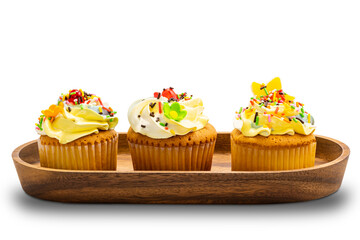 Vanilla cup cakes with colorful butter cream frosting and multicolored sprinkles in wooden tray on white background with clipping path.