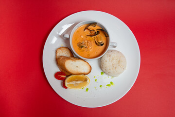 tomato soup with mussels and rice. red background. top view. flat lay.