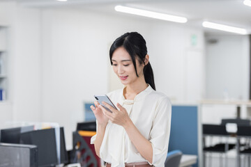 オフィスでスマホを操作する日本人ビジネスウーマン