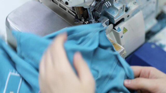 The worker is sewing a textile with a sewing machine in a fabric factory.
