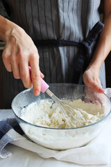 Household. Hands of a housewife knead the dough in a large bowl with a whisk. Family celebration.