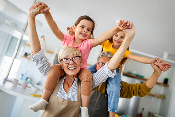 Portrait of happy elderly couple and grandchildren playing together