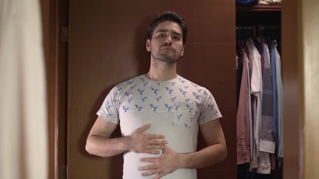 Young man insecure of figure infront of mirror