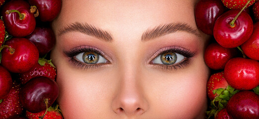  Beautiful woman with fashion makeup and a vivid background.   Young girl with bright makeup and a berry background. © Valua Vitaly