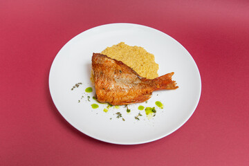 sea bass with rice on white plate. red background. top view. flat lay.