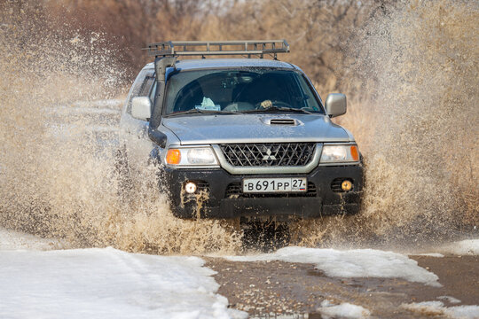 KHABAROVSK, RUSSIA - MARCH 25, 2017: Mitsubishi Pajero Sport on dirt road in early spring making splashes from a puddle