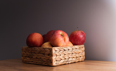 Some eco red apples in dark light inside a wood basket on a table