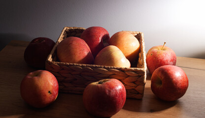 Some eco red apples in dark light inside a wood basket on a table