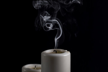 smoldering extinguished candle and smoke on black background