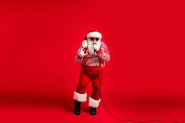 Full length body size view of his he handsome bearded fat overweight cool talented Santa vocalist rock roll star singing hit showing horn sign isolated bright vivid shine vibrant red color background