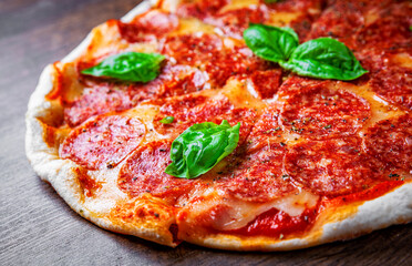Pepperoni Pizza with Mozzarella cheese, salami, Tomato sauce, pepper, Spices and Fresh basil. Italian pizza on wooden table background