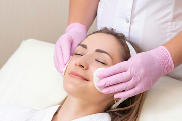 Fototapeta na wymiar cosmetology. Close up picture of lovely young woman with closed eyes receiving facial cleansing procedure in beauty salon.