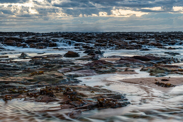 Rock platform, cascades and splashes with rain clouds by the seaside