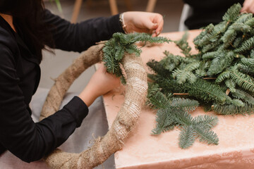 Woman makes christmas wreath on the table. Florist work concept before christmas holidays.