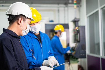 Asian engineer foreman discuss project on digital tablet with factory worker in industrial construction. industry people in face mask to prevent flu virus during company reopen. new normal working