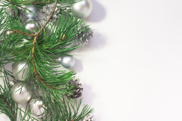 Light Christmas background with silver balls, cones and pine branches on a white background. New Year celebration.