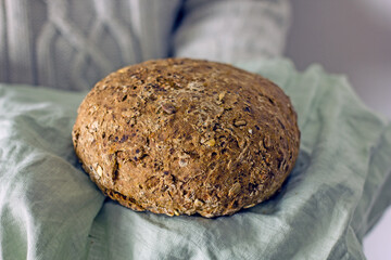 Gluten free homemade bread in the hands of a man without a face in a gray sweater, copy space
