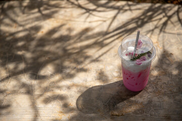 Iced Pink milk smoothie in plastic cup with sunlight on summer.