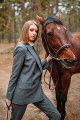 Girl rider standing next to the horse. The girl holds the horse's bridle