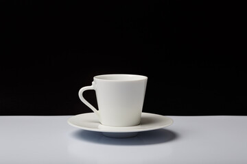 White ceramic coffee cup on white table with black background