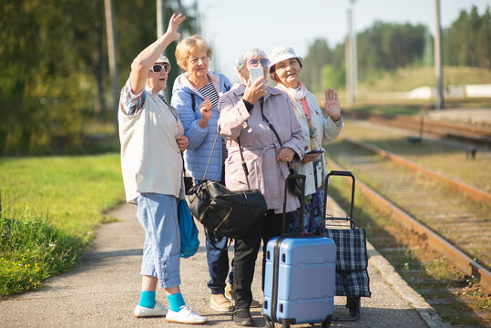 Group of senior women take a self-portrait on a platform waiting for a train to travel during a COVID-19 pand