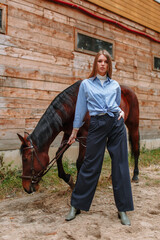 Girl rider standing next to the horse. The girl holds the horse's bridle